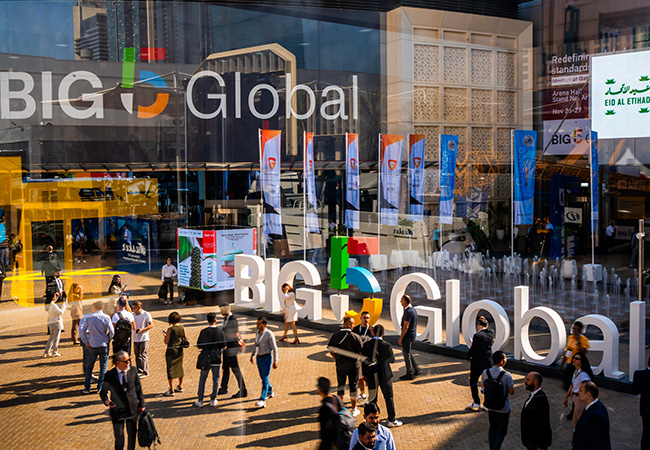 A group of people walking in front of a glass building in Dubai